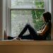 Woman sitting quietly by a window, reflecting on feeling emotionally disconnected