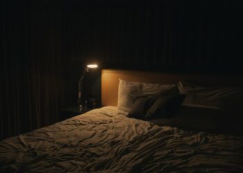 A softly lit bedside lamp beside a bed at night, creating a calm setting for winding down before sleep